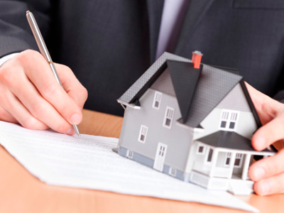 a man writes on paper and holds a house with one hand
